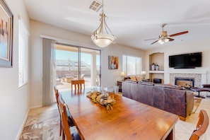 A spacious living area with a wooden dining table, a sofa, a TV, and a fireplace. - Contemporary & comfortable home with a pool, WiFi, washer/dryer & central air-conditioning (Oro Valley)