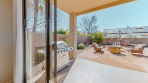 Eine Terrasse mit Grill, Gartenmöbeln und Blick auf den Garten.