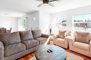 Un salon moderne avec un canapé gris, des fauteuils beige et une table basse ronde.