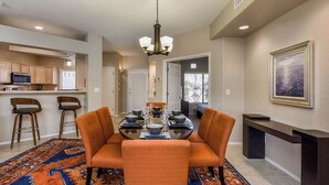 A dining area with a round table, orange chairs, and a patterned rug. - Comfortable condo with renovated kitchen, patio, pool, hot tub & fitness center (Oro Valley)