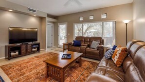 A living room with a TV, leather sofas, a coffee table, and a patterned rug. - Comfortable condo with renovated kitchen, patio, pool, hot tub & fitness center (Oro Valley)
