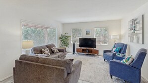 A living room with a sofa, armchairs, a TV, and artwork on the walls. - Stylish Sam Hughes Escape With Private Yard, Dogs OK & Free WiFi (Tucson)