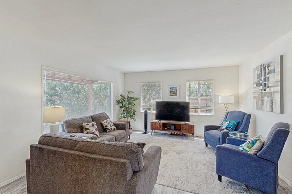 A living room with a sofa, armchairs, a TV, and artwork on the walls. - Stylish Sam Hughes Escape With Private Yard, Dogs OK & Free WiFi (Tucson)