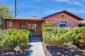 A single-story brick house with a red roof, a visible number '123' on the front, and a covered porch with a chair. - Stylish Sam Hughes Escape With Private Yard, Dogs OK & Free WiFi (Tucson)