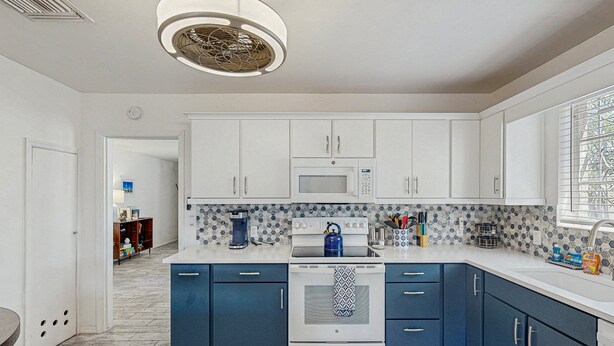 A modern kitchen with white cabinets, a blue countertop, and a stainless steel kettle. - Stylish Sam Hughes Escape With Private Yard, Dogs OK & Free WiFi (Tucson)