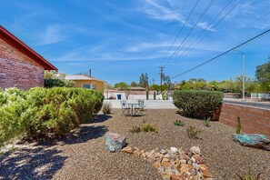 A residential area with a gravel driveway, a patio with outdoor furniture, and a brick building. - Stylish Sam Hughes Escape With Private Yard, Dogs OK & Free WiFi (Tucson)