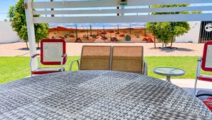 A patio area with a round woven table and two cushioned chairs with red frames. - Snowbird-friendly home with central AC, washer/dryer & free WiFi - near golf (Phoenix)