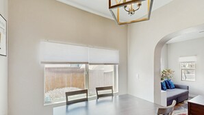 A dining area with a large table, chairs, and a window with blinds.