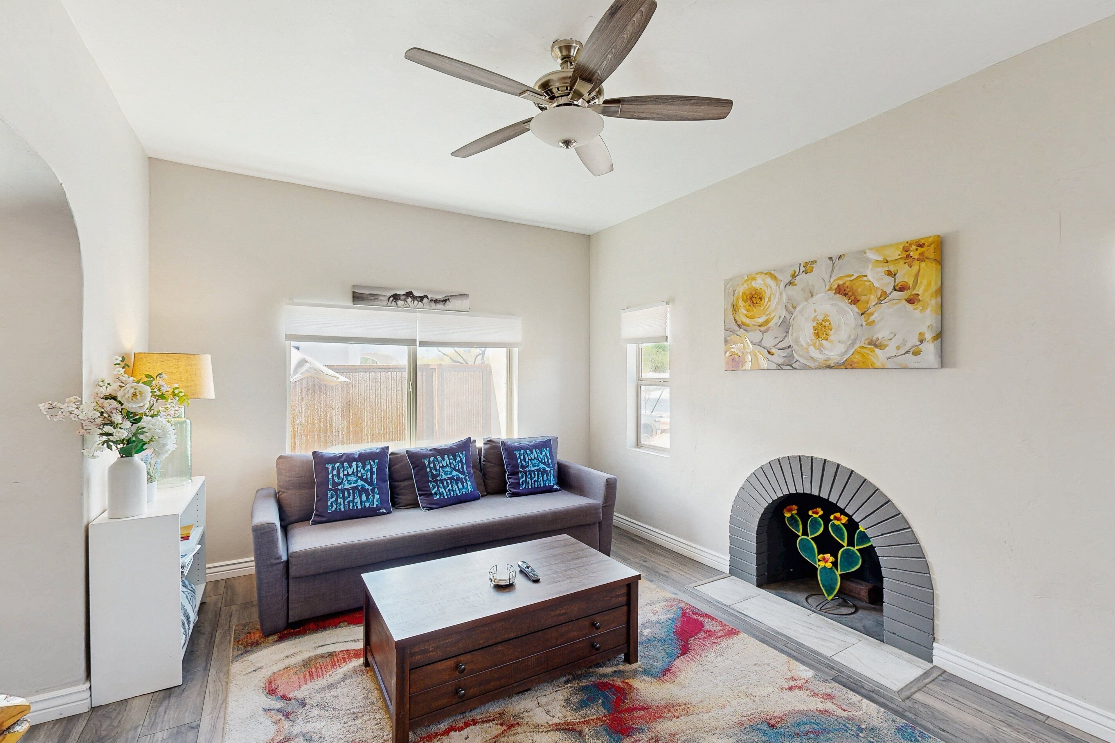 A living room with a gray sofa, a coffee table, a fireplace, and a ceiling fan.