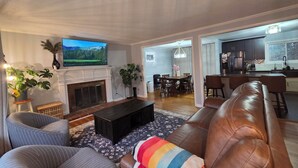 Ein Wohnzimmer mit Kamin, Fernseher, Essbereich und Küche.