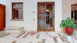 Un edificio con un portón metálico grande, una ventana pequeña y una planta en maceta.