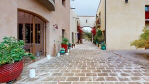 Una estrecha calle adoquinada bordeada de edificios con balcones y plantas en macetas.