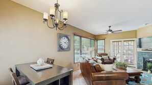 A living room with a fireplace, a dining area with a table and chairs, a sofa, and a ceiling fan. - Snowbird-friendly condo w/shared heated outdoor pool, hot tub & tennis (Tucson)