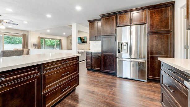 A spacious kitchen with dark wooden cabinets, stainless steel appliances, and a large island. - Dog-friendly home with enclosed yard, pool, putting green, grill, foosball, & AC (Scottsdale)