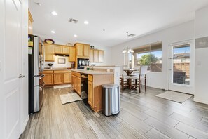A modern kitchen with wooden cabinets, a stainless steel refrigerator, and a built-in oven.