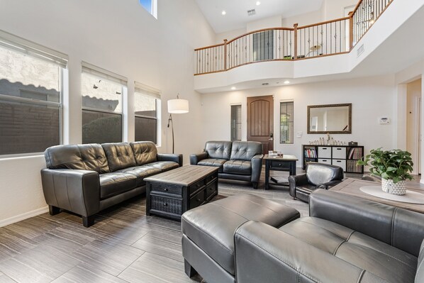 A spacious living room with leather sofas, a coffee table, and a staircase leading to an upper level.