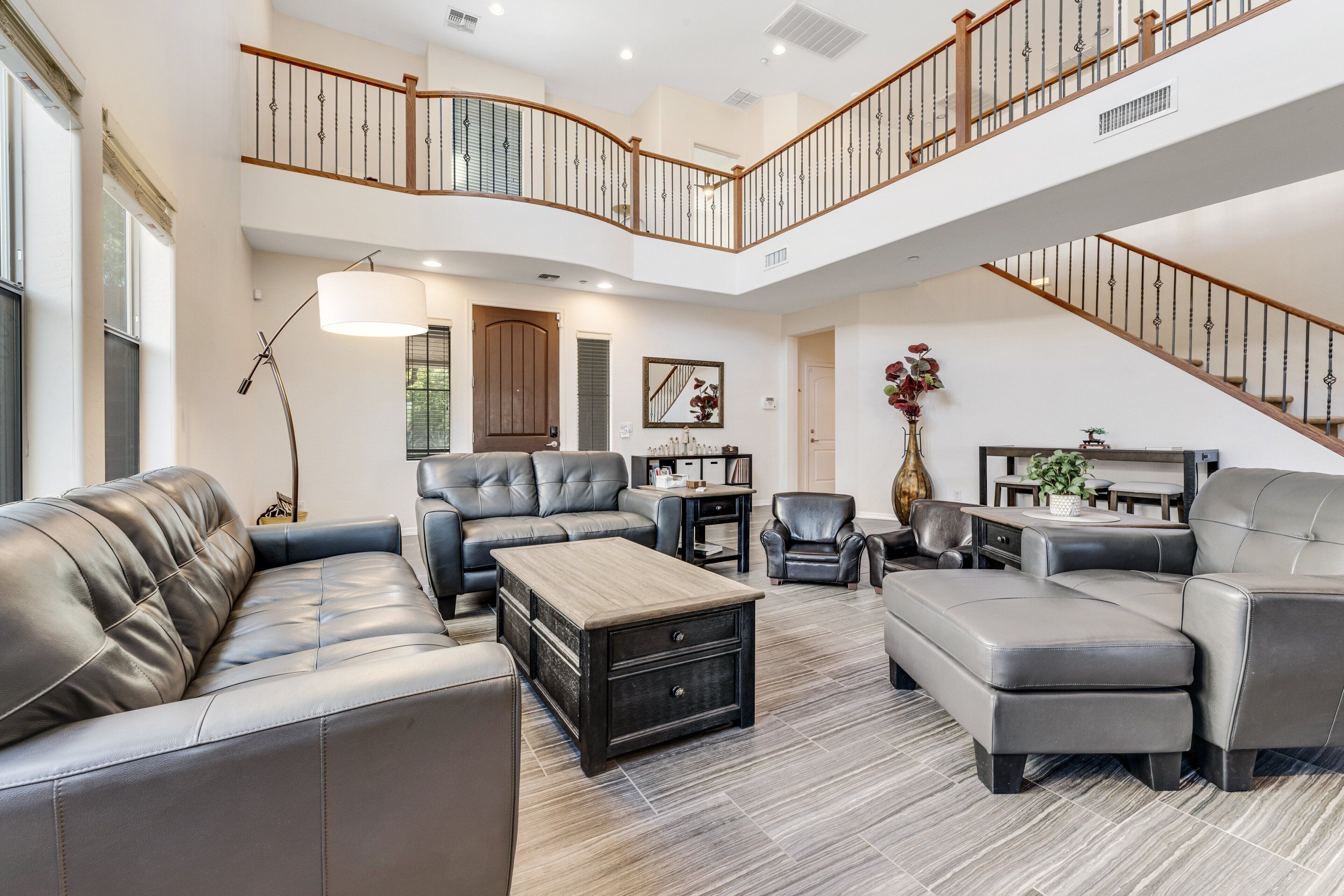 A spacious living area with a high ceiling, a staircase, and a view of the outdoors.