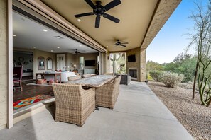 An outdoor patio with wicker furniture, ceiling fans, and a view of the surrounding landscape. - Golf-Course View Condo with Central AC & Washer/Dryer - Shared Pool & Hot Tub (Scottsdale)