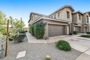 A modern two-story house with a garage, surrounded by a landscaped garden with gravel, shrubs, and a small cactus. - Golf-Course View Condo with Central AC & Washer/Dryer - Shared Pool & Hot Tub (Scottsdale)