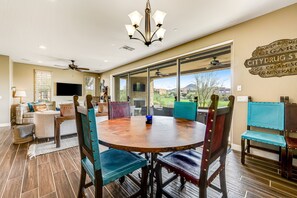 A spacious dining area with a round wooden table, multiple chairs, and a ceiling fan. - Golf-Course View Condo with Central AC & Washer/Dryer - Shared Pool & Hot Tub (Scottsdale)