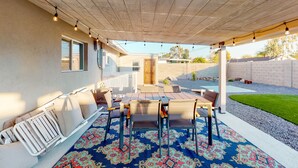 A covered patio with a table and chairs, a patterned rug, and string lights. - Modern Ranch with Private Putting Green, Fast WiFi, Central AC, & Great Location (Scottsdale)