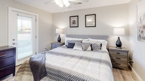 A bedroom with a bed, two bedside tables, a ceiling fan, and two wall-mounted lamps. - Modern Ranch with Private Putting Green, Fast WiFi, Central AC, & Great Location (Scottsdale)