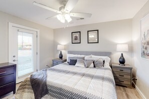 Ein Schlafzimmer mit einem Bett, zwei Nachttischen, einem Deckenventilator und zwei Wandlampen.