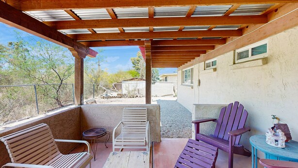 A covered patio with wooden benches and chairs, a small table, and a view of a residential area. - Fun, Dog-Friendly Home w/ Game Room, Ping-Pong, Patio, Fast WiFi, & AC (Tucson)