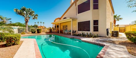 A modern two-story house with a swimming pool, surrounded by palm trees and a well-maintained garden.