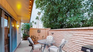 An outdoor patio with a round table and four chairs, a brick wall, and a grill. - Dog-Friendly Home near Downtown with Private Patio, Gas Grill, Central A/C, W/D (Sun City)