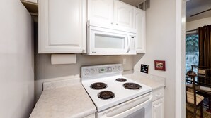 A kitchen with white cabinets, a white stove, and a microwave. - Dog-Friendly Home near Downtown with Private Patio, Gas Grill, Central A/C, W/D (Sun City)