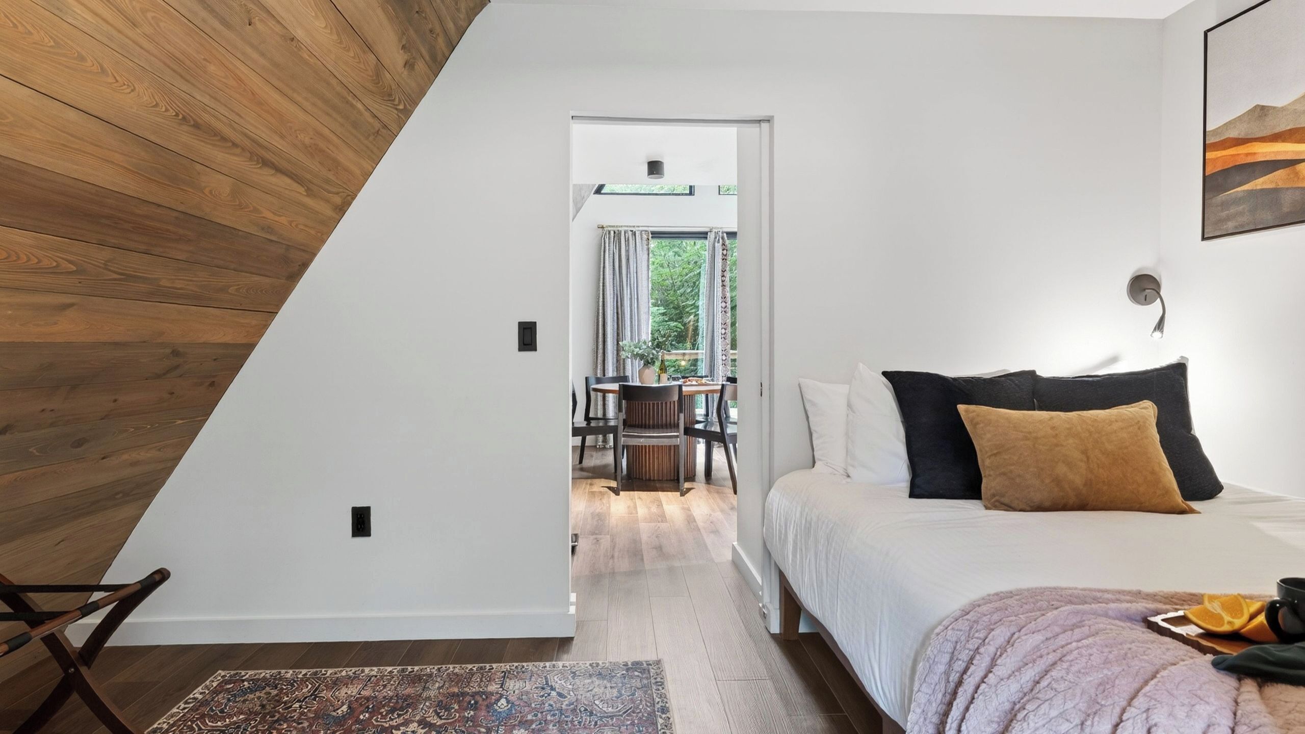 A bedroom with a bed, pillows, a nightstand, a window, and a view of the outdoors.