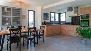Uma cozinha moderna com área de jantar, apresentando uma ilha de madeira, armários embutidos e uma janela ampla.