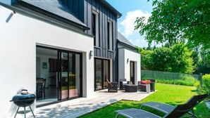 Uma casa moderna com um pátio, área de estar externa e churrasqueira.