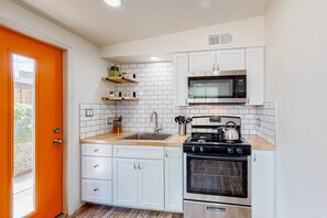 A compact kitchen with white cabinets, a microwave, an oven, and a sink. - Modern Dog-Friendly SW Retreat w/ Covered Parking & Pastries Delivered To You!!! (Tucson)
