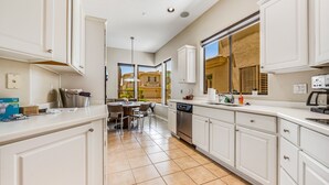 Una cucina moderna con mobili bianchi, un'area pranzo e un'ampia finestra che offre vista all'esterno.