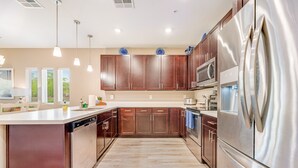A modern kitchen with stainless steel appliances, wooden cabinets, and pendant lighting. - Spacious townhouse with fast WiFi, central AC, washer/dryer, pool, & hot tub (Mesa)