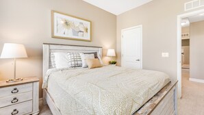 A bedroom with a bed, bedside tables, a nightstand, a door, and a framed picture on the wall. - Spacious townhouse with fast WiFi, central AC, washer/dryer, pool, & hot tub (Mesa)