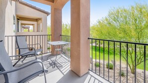 A balcony with two chairs and a table, overlooking a landscaped garden with trees and shrubs. - Spacious townhouse with fast WiFi, central AC, washer/dryer, pool, & hot tub (Mesa)
