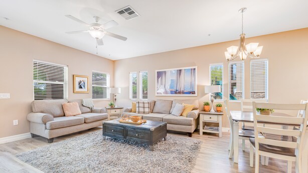 A living room with a sofa, coffee table, and dining table. - Spacious townhouse with fast WiFi, central AC, washer/dryer, pool, & hot tub (Mesa)