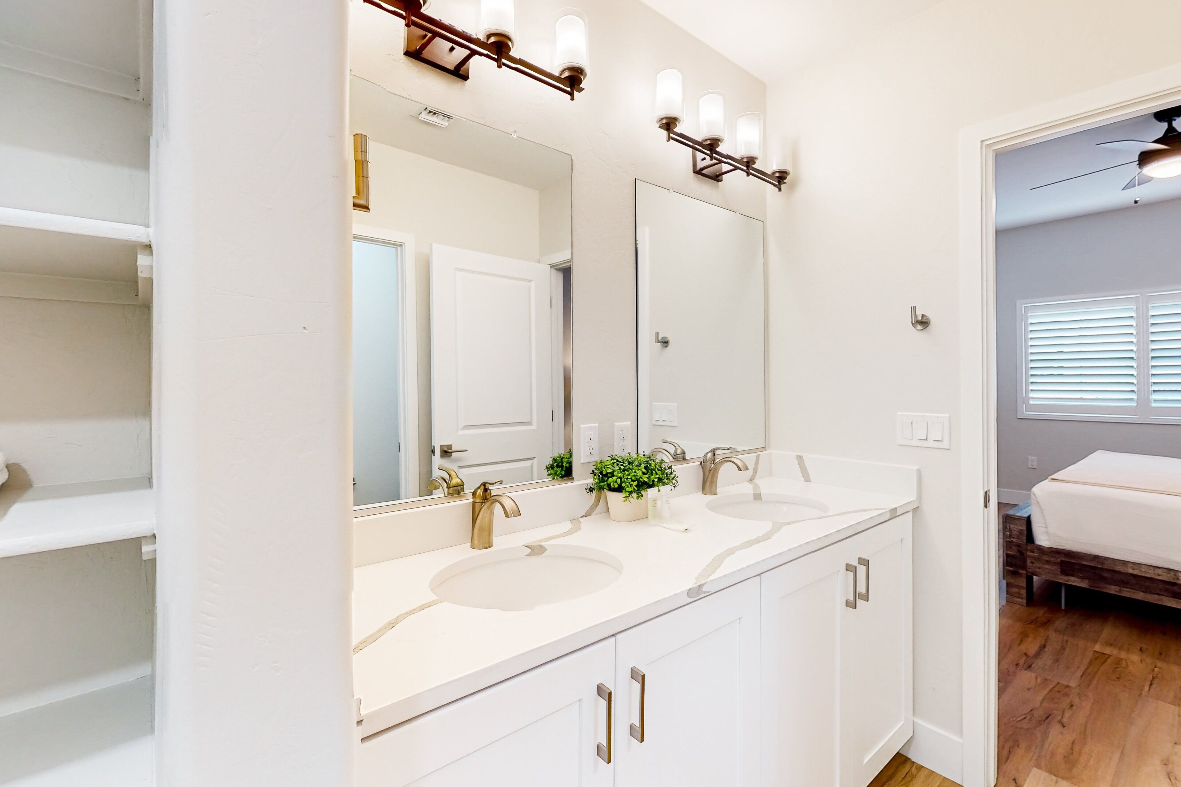 A bathroom with two sinks, a large mirror, and a vanity with cabinets.