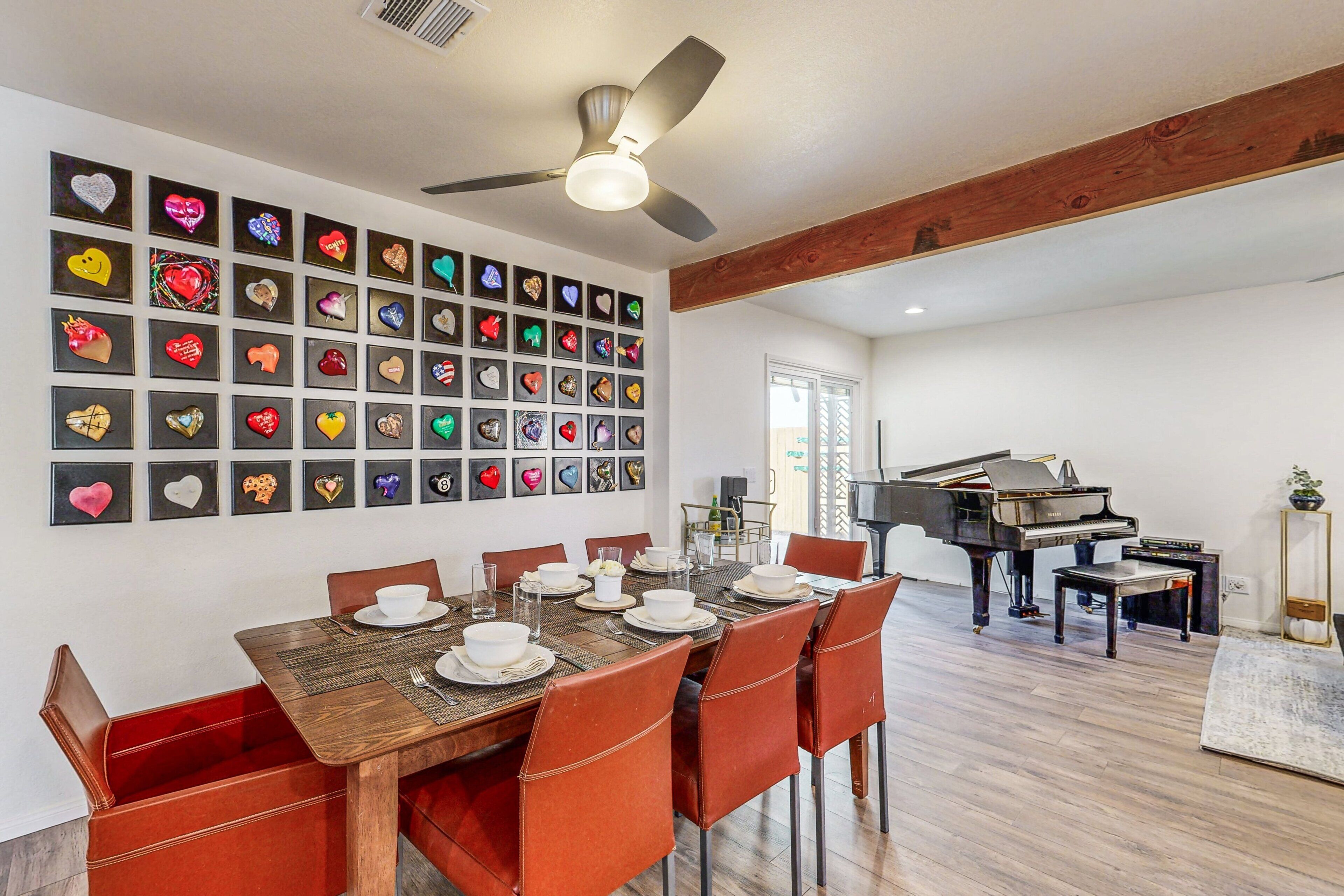 A dining area with a wooden table, red chairs, and a wall of heart-shaped decorations.