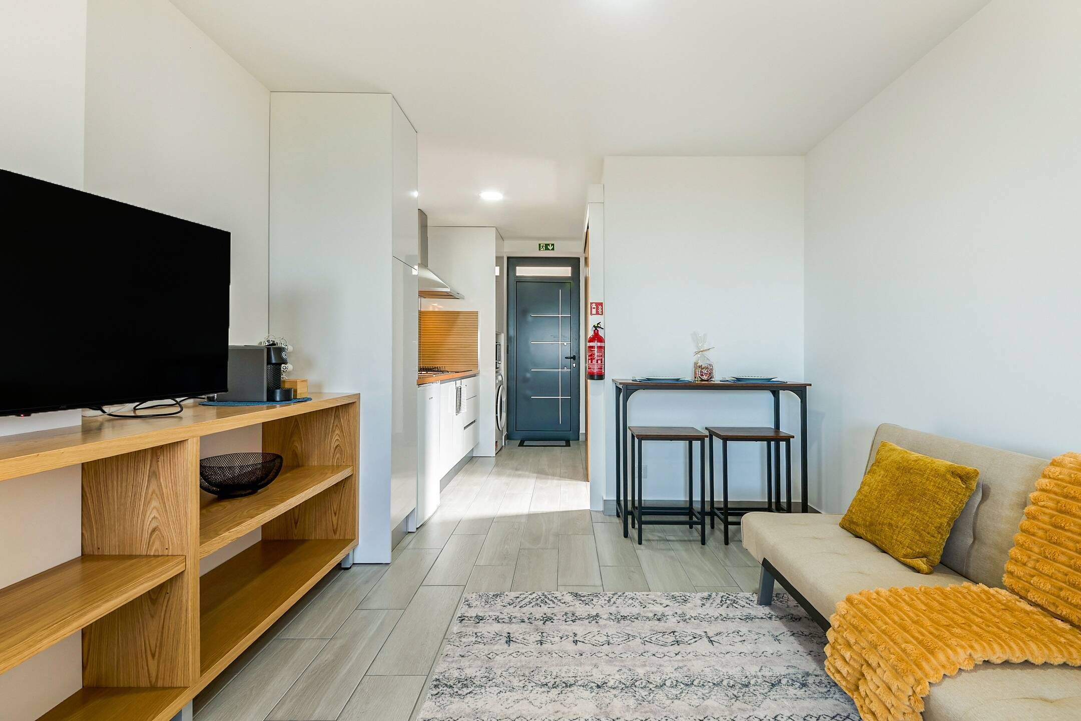 A modern living room with a sofa, TV, wooden shelves, and a small table.