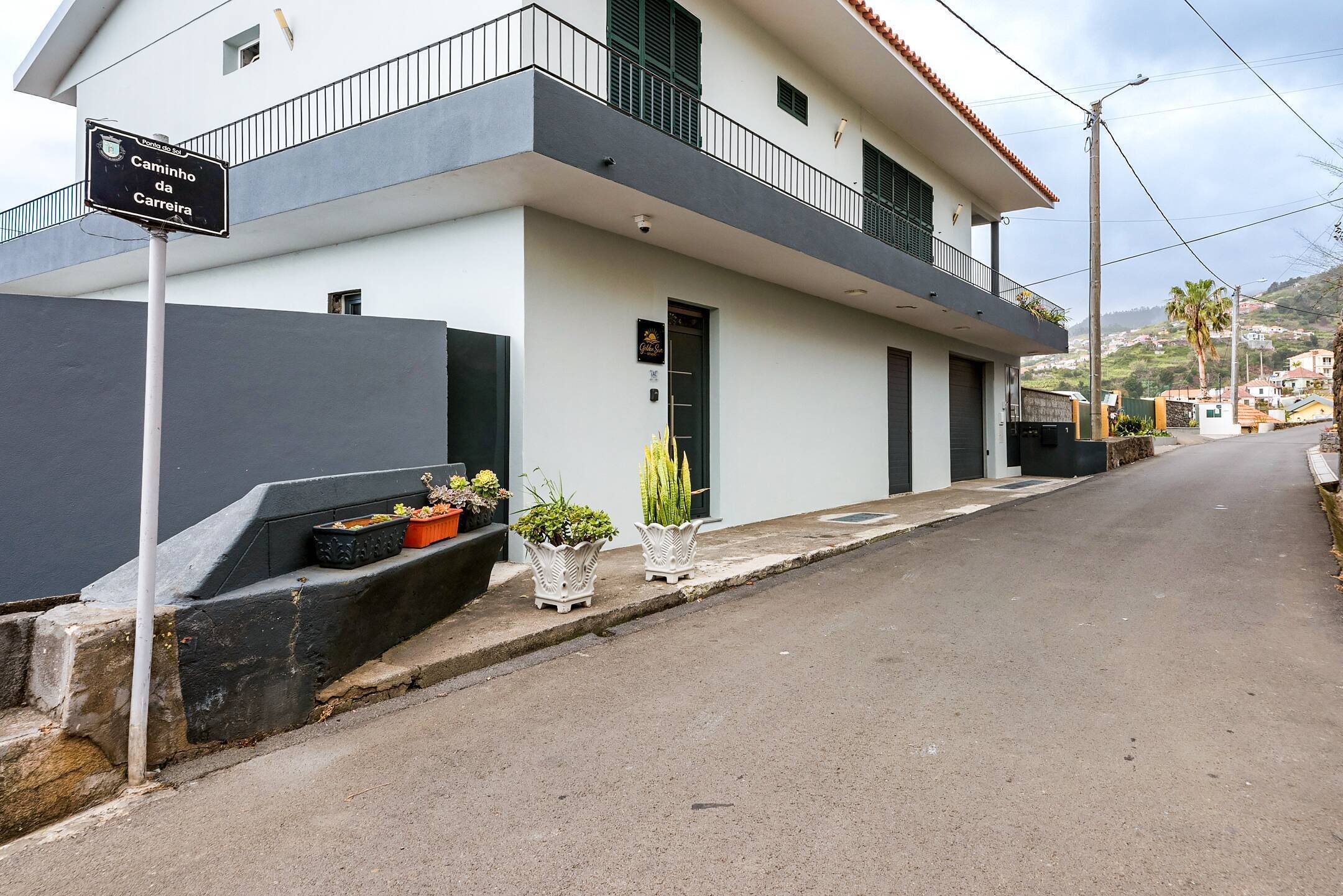 Un bâtiment à deux étages doté d’un balcon, d’une enseigne indiquant « Camino da Carreira » et de plantes en pot sur le trottoir.