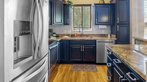 Una cocina moderna con armarios oscuros, electrodomésticos de acero inoxidable y encimera de granito.