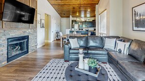 Una sala de estar moderna con chimenea de piedra, sofá de cuero y una zona de comedor al fondo.