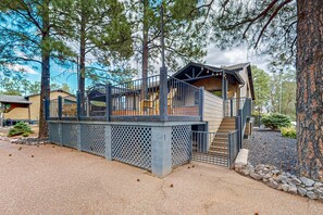 A two-story building with a wooden deck and stairs leading to a covered porch. - Luxury home on the fairway with deck, fire pit, bbq grill (Show Low)