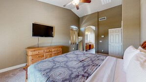 A bedroom with a bed, a ceiling fan, a TV, a dresser, and a mirror. - Spacious home surrounded by palms with pool, grill, children (Litchfield Park)