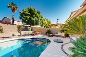 Un jardin avec une piscine, du mobilier d’extérieur et une pergola.