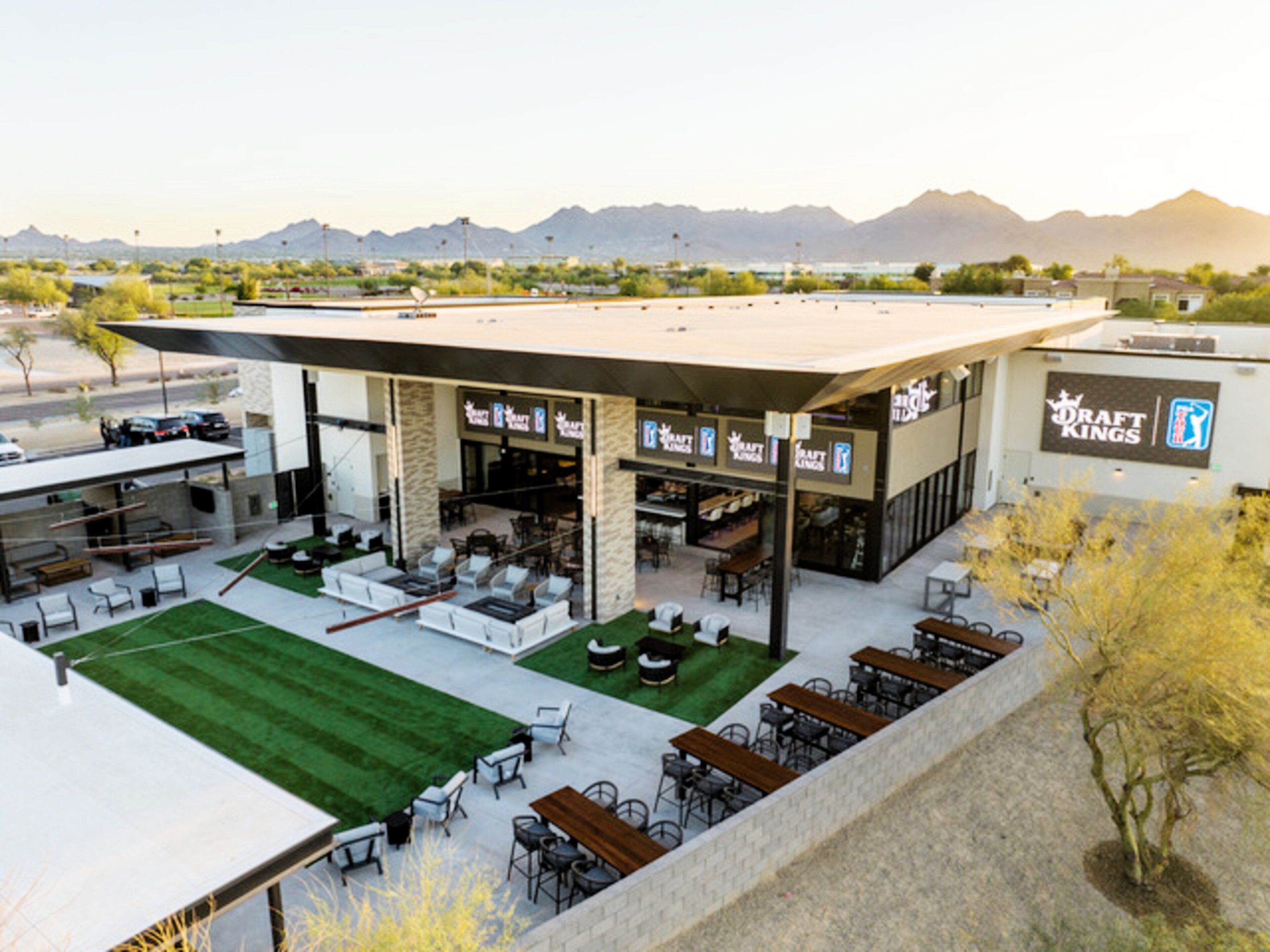 A modern outdoor dining area with multiple seating arrangements and a view of mountains in the background.
